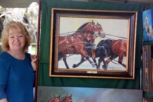 Equestrian artist Moe Hahn shows off a completed painting of Chester Weber’s winning four-in-hand team.